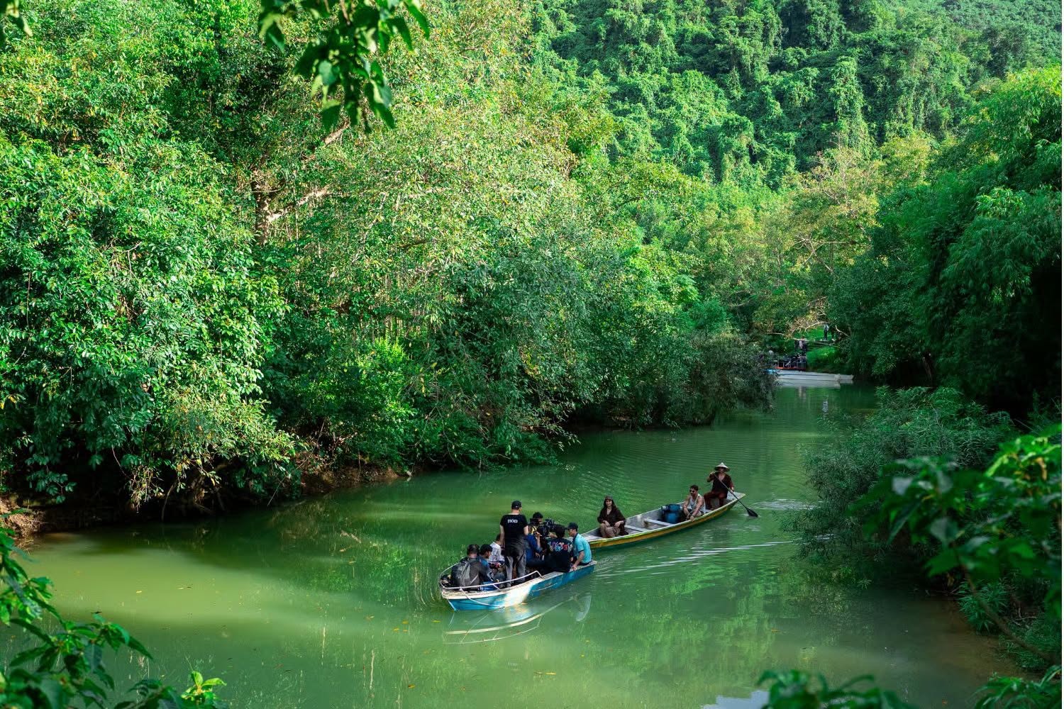 Thuyền và ê-kíp ghi hình trên dòng sông giữa cảnh quan hang động Phong Nha