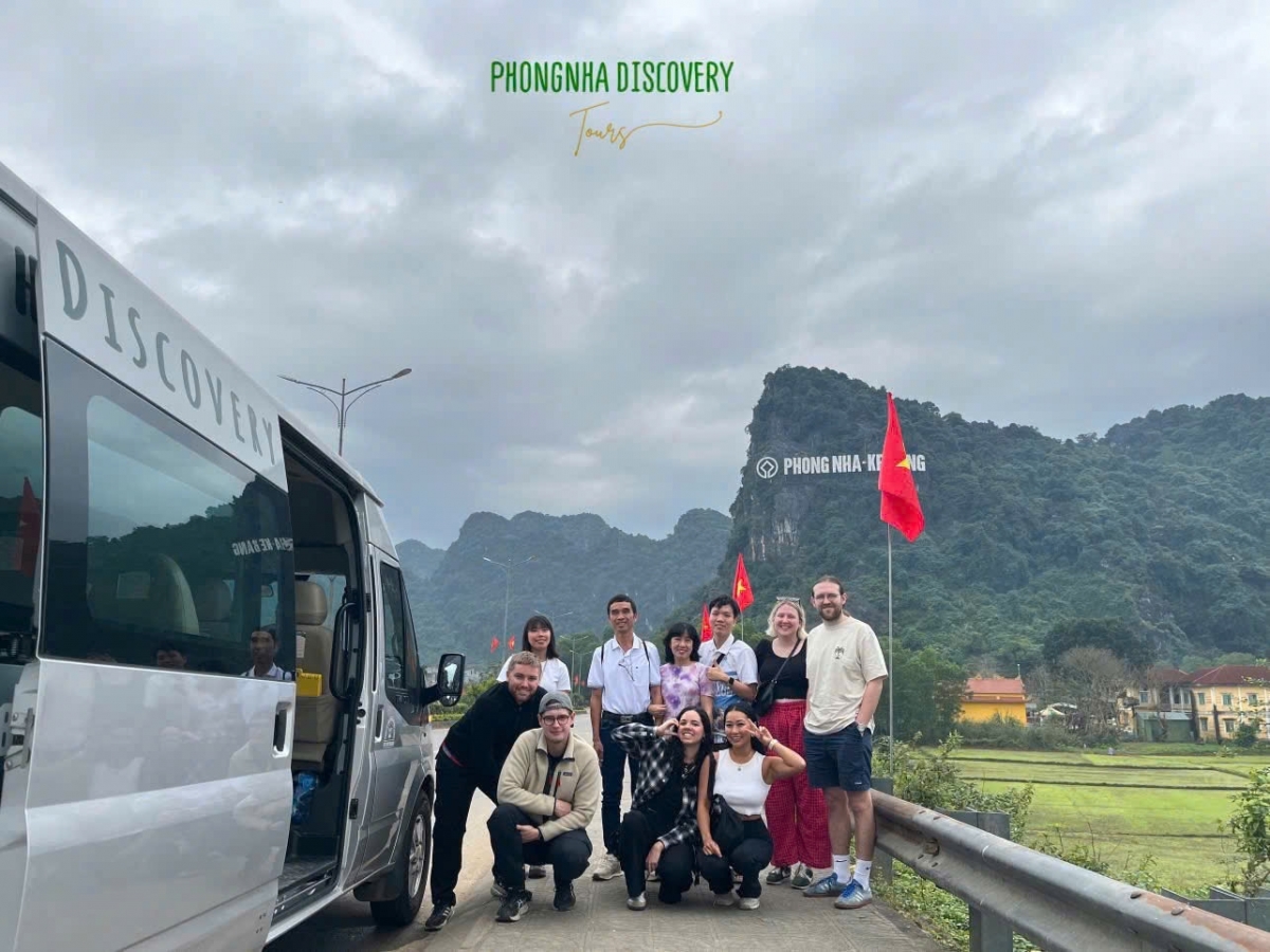 tourists-phong-nha-posing A group of tourists posing for a souvenir photo in front of Phong Nha Cave, next to the Phong Nha Discovery Tours vehicle.